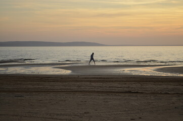 Fototapeta na wymiar silhouette of a person walking on the beach
