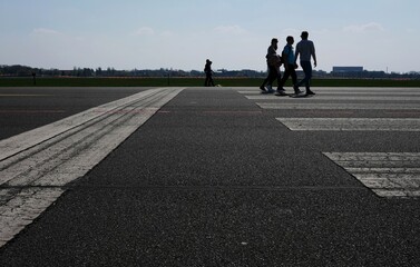 silhouetted people walking on airfield and street - 387151965