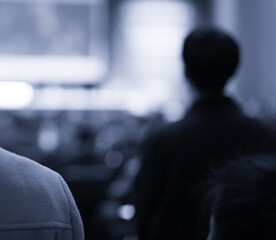 Audience watching a presentation. Presenter on stage giving talk to crowd of people. Speaker at investor pitch conference. 
Defocused blurred presenter during conference lecture event. Seminar photo.