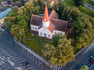 Top down view on Lutheran church with trees surrounding it, half empty parking lot next to it © Reinholds