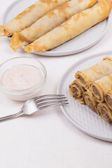 Meat stuffed crepes served with sauce.