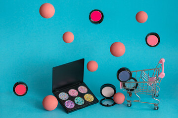 New eyeshadows palette on a blue background. Levitating balls around eyeshadow palette and cart of supermarket 