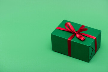 colorful gift box with red ribbon and bow on green background with copy space