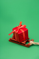 red gift box on decorative wooden sleigh on green background