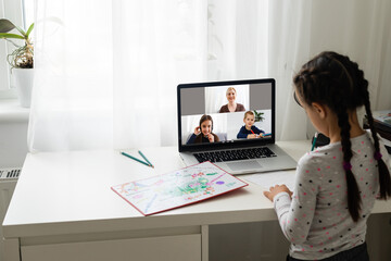 happy little child girl using laptop for studying online. child answers the teacher's question. online education concept