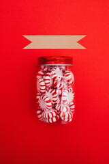 Mint candies in a jar on red background. Christmas treats.