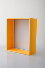 Yellow orange open cardboard box or carton on grey background, template, mockup, sideview.