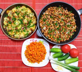 Chanterelle mushrooms and potatoes fried with green onions in two pans and cloudberry berries for a snack for dinner with friends, Top view