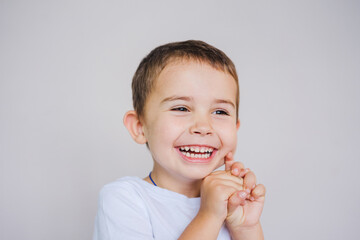 Little boy laughs holding his hands to his face. Close-up portrait of a Caucasian child.