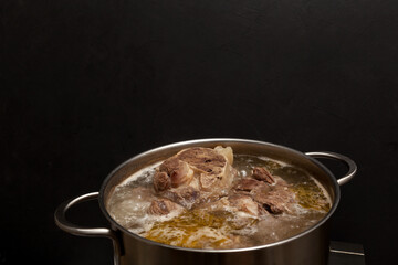 Beef bone broth is cooked in a pot. Bones contain collagen, which provides the body with amino acids, which are the building blocks of proteins