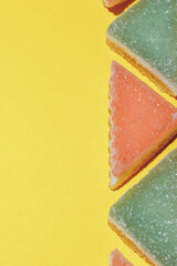 Colorful triangular jelly candy on yellow background. Macro shot.