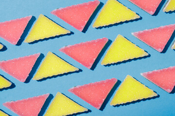 Pattern made of multicolored triangular jelly candy on blue background. Macro shot.