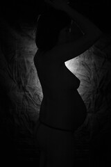 silhouette of a naked sexy pregnant woman on a black background
