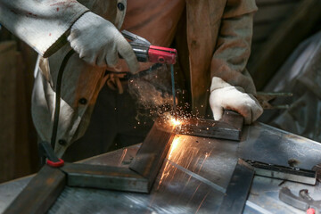 welder welds a metal structure in a workshop with electrical welding