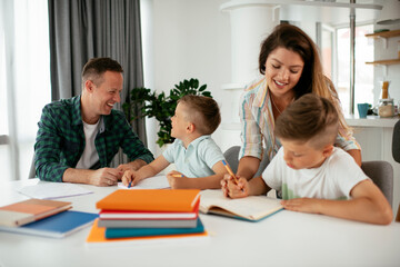 Parents helping the kids with their homework. Litlle boys learning at home