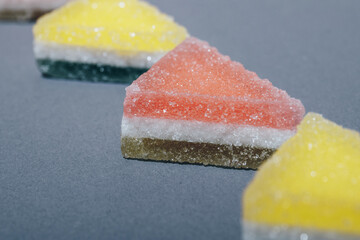 Colorful triangular jelly candy on gray background.