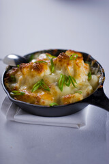 Steakhouse side dishes. Asparagus, salad, tomatoes, mashed potatoes, red onions, cream cauliflower, pickled peppers, seasoned meats served in cast iron skillet. Traditional appetizer items.