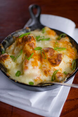 Steakhouse side dishes. Asparagus, salad, tomatoes, mashed potatoes, red onions, cream cauliflower, pickled peppers, seasoned meats served in cast iron skillet. Traditional appetizer items.
