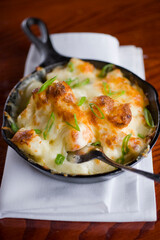 Steakhouse side dishes. Asparagus, salad, tomatoes, mashed potatoes, red onions, cream cauliflower, pickled peppers, seasoned meats served in cast iron skillet. Traditional appetizer items.