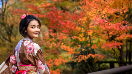young woman tourist wearing blue kimono and umbrella took a walk in the park in autumn leaves season
