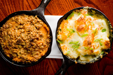 Steakhouse side dishes. Asparagus, salad, tomatoes, mashed potatoes, red onions, cream cauliflower, pickled peppers, seasoned meats served in cast iron skillet. Traditional appetizer items.
