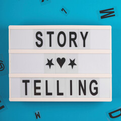 Storytelling is written on a decorative board among black letters on a light blue background. Marketing and content creating through telling stories
