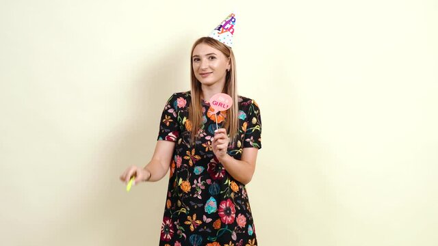 The happy young mother holds a sticker with itis a girl in her hand. The beautiful young woman dressed in a colorful dress celebrates the birth of a little girl. Holiday concept. Caucasian young woman