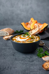 Pumpkin soup with ingredients on dark background. Vegetarian autumn pumpkin cream soup with croutons.