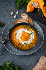 Pumpkin soup with ingredients on dark background. Vegetarian autumn pumpkin cream soup with croutons.