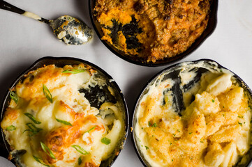 Steakhouse side dishes. Asparagus, salad, tomatoes, mashed potatoes, red onions, cream cauliflower, pickled peppers, seasoned meats served in cast iron skillet. Traditional appetizer items.