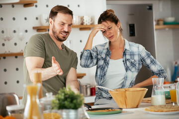 Young couple making pancakes at home. Loving couple having fun while cooking.
