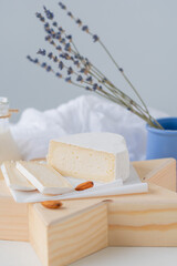Slices of traditional farm cheese with white mold on a wooden stand in the shape of a star