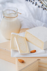 Slices of traditional farm cheese with white mold on a wooden stand in the shape of a star