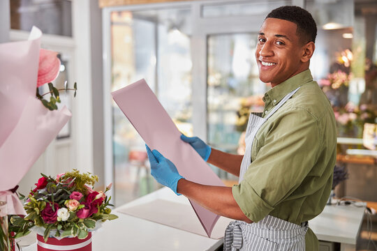 Excited florist shop salesman with pink gift paper