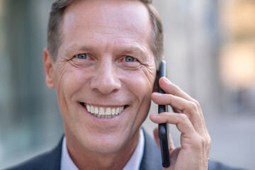 Smiling mature businessman speaking on the phone outside