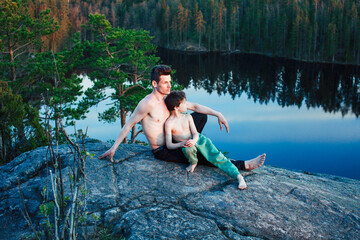 Fototapeta premium middle age man with little cute son doing sport yoga on the top of the mountain together, happy family lifestyle people outdoor, summer wild nature for training