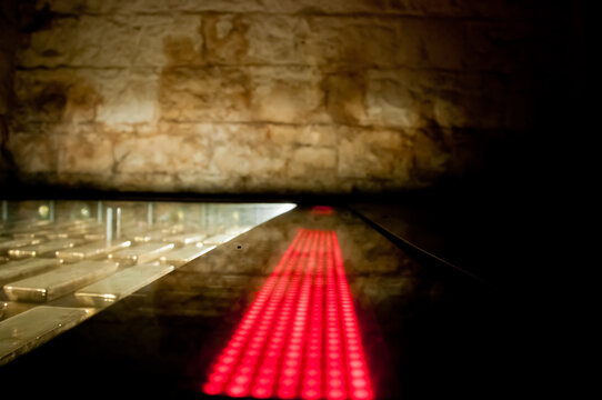 Many gold bars kept in the dark of a safe strong room