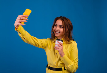 Smiling young girl making selfie photo on smartphone over blue background