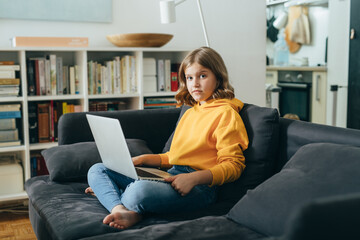teenage girl sitting on sofa and using laptop computer at home