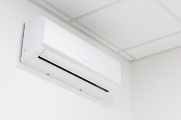 white heating and cooling air conditioner on white wall in office or home