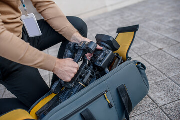 Fototapeta premium Close-up of operator standing on one knee, taking camera out of the case