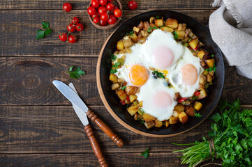 Fried eggs with vegetables  - shakshuka in a frying pan and rye bread on an old wooden background. Late breakfast. Rustic style. Middle eastern traditional dish.  Flat lay. Top view