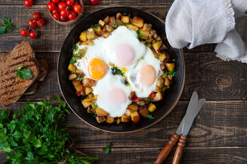 Fried eggs with vegetables  - shakshuka in a frying pan and rye bread on an old wooden background. Late breakfast. Rustic style. Middle eastern traditional dish.  Flat lay. Top view