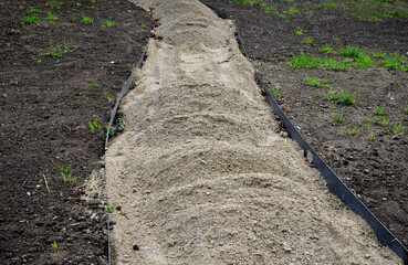 construction of a threshing gravel sidewalk, installation of a steel strip as a curb path. between them there is a gravel mixture which is compacted by means of a selection plate. suitable for gardens