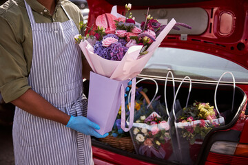 Florist store worker packing flowers to a trunk