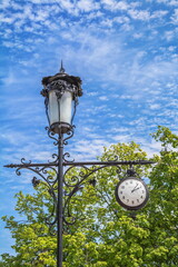 Fototapeta na wymiar City lantern with clock, decorated with beautiful art forging
