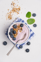 Blueberry yogurt with granola and fresh berries on white background. Healthy breakfast