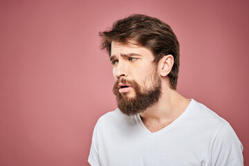 Obraz premium Emotional bearded man in white T-shirt discontent pink background