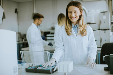 Fototapeta premium Female scientist in white lab coat standing in the biomedical lab
