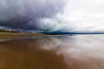 View of the Snowdonia Mountain Range from Newborough Beach with threatening rain clouds overhead, Isle of Anglesey, North Wales 